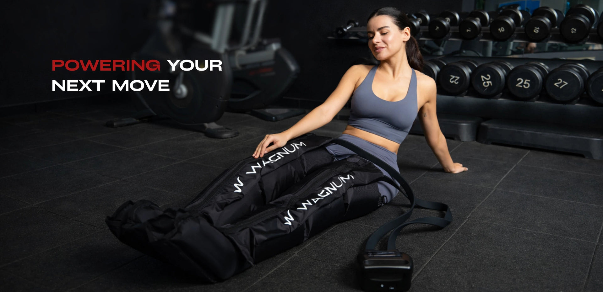 Woman sitting on the floor while using the WAGNUM Elite Air compression boots in a gym setting.